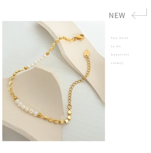 Detailed macro view of French chic gold chain bracelet with freshwater pearls on white marble