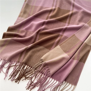 Dettaglio della sciarpa a quadri viola e rosa con texture morbida e nappe decorative
