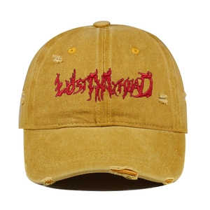 Detail of vintage washed mustard baseball cap with red gothic lettering and frayed holes