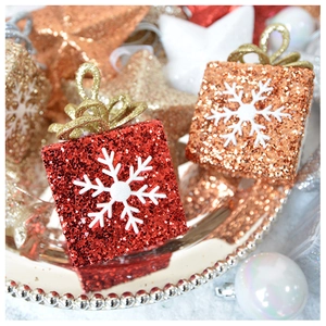 Close-up of red and bronze glitter gift box ornament with a white 3D snowflake