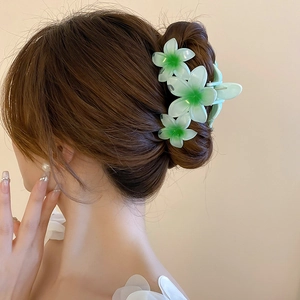 Detail view of large green gradient acrylic flower hair claw clip on a woman's bun hairstyle