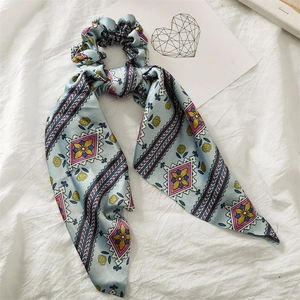 Blue satin scrunchie with geometric floral patterns on white fabric background
