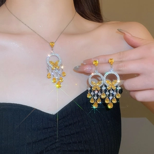 Close-up of model wearing silver butterfly tassel necklace and earrings with yellow stones