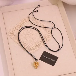 Detailed macro shot of adjustable black cord and gold pine cone pendant necklace