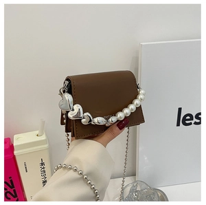 Detail of dark brown mini square bag featuring white pearl and silver heart hand chain