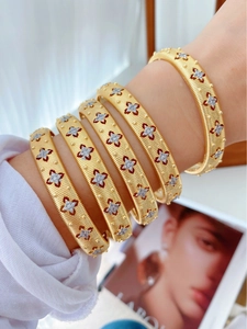 Macro shot of five stacked gold brushed metal bangles with star-set cubic zirconia stones