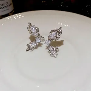 Elegant silver butterfly ear cuff with sparkling zircon crystals on white ceramic plate