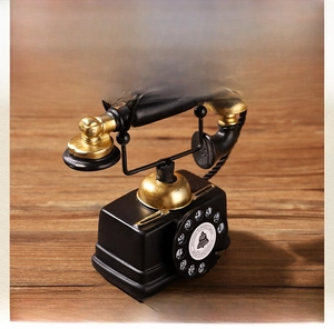 Detail of vintage resin telephone model featuring a classic black and gold rotary dial
