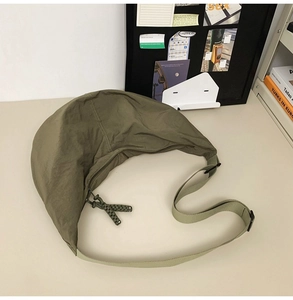 Détail de la sacoche en nylon vert avec bandoulière réglable et détail de fermeture à nœud