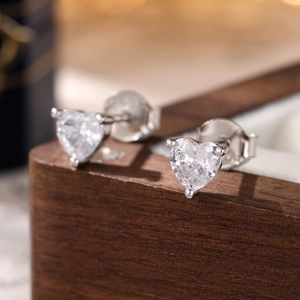 S925 silver heart stud earrings with sparkling cubic zirconia on a wooden jewelry box
