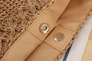 Detailed macro view of metal magnetic snap closure and woven lining on a straw beach bag