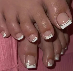 Close-up of French pedicure style press-on toenails with white tips and pink base