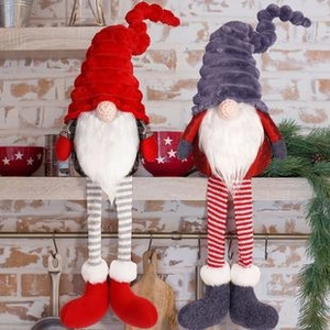 Detail of red and grey Christmas gnomes with striped legs on a wooden shelf