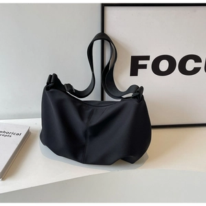Minimalist black nylon tote bag shown in a professional studio setting on white surface