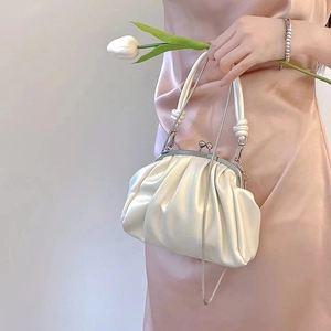 Elegant white pleated cloud bag with metallic clasp and chain strap held by a model