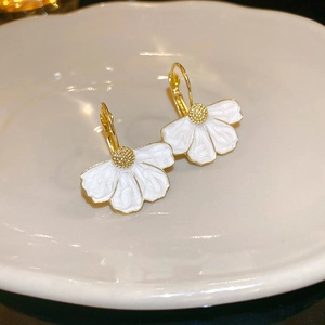 Vintage style white enamel flower earrings with gold center petals in a ceramic dish