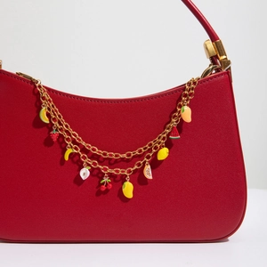 Detail of red faux leather handbag featuring 18K gold fruit charm chain decoration