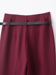 Detail of burgundy high waist trousers with slim black leather belt and stitching