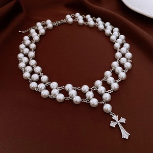 Close-up of double-layer pearl necklace with a sparkling zircon cross pendant detail