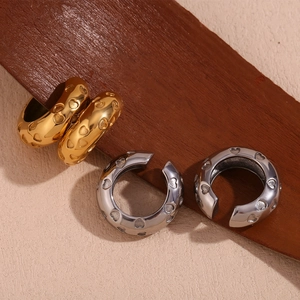 Detail of gold and silver heart-engraved ear cuffs on a vintage wooden background