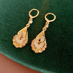Macro shot of vintage gold teardrop earrings with champagne gemstones on green velvet