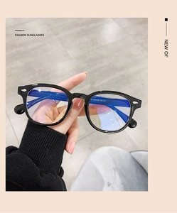 Détail de lunettes rondes rétro à monture noire avec clous argentés et verres anti-lumière bleue