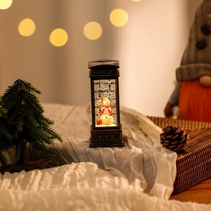 Macro detail of a bronze British telephone booth lantern with a snowman and snow glitter