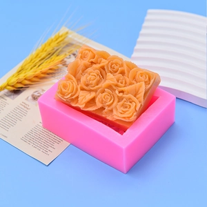 Pink silicone rose flower mold with finished embossed soap on a blue background