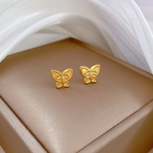 Macro shot of 3D hollow butterfly stud earrings in gold finish on velvet display