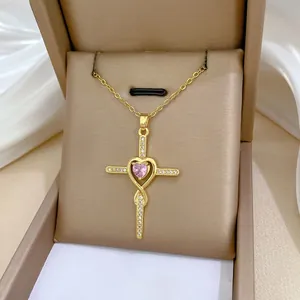 Detail of gold cross pendant with pink heart gemstone on luxury satin display