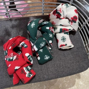 Close-up of thick knitted Christmas scarves featuring festive reindeer and snowflake patterns