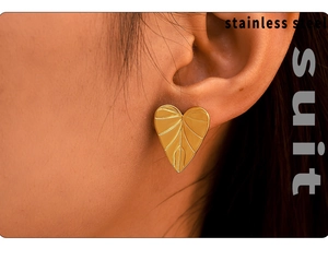Close-up of golden leaf-shaped stainless steel earring worn on a person ear
