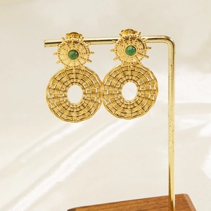 Detail of bohemian gold drop earrings featuring green natural stones on a display stand