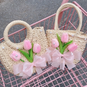 Detail of straw woven handbag with pink tulip floral decor and silk bow in a pink cart