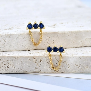 Detail shot of gold earrings with three blue cubic zirconia and delicate chain drops