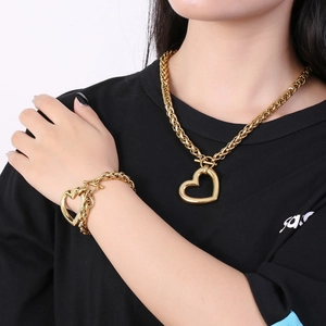 Golden heart pendant necklace and bracelet set shown on model in black top