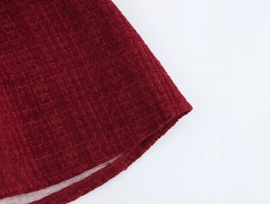 Détail macro de la texture du tissu en tweed rouge vin et de l'ourlet arrondi de la robe