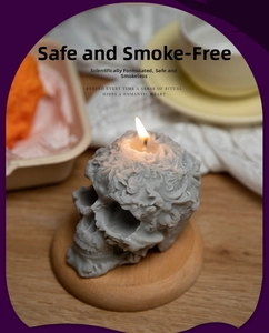 Detailed view of grey skull candle with baroque carvings burning on a wood tray