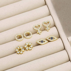 Set of four gold-plated stud earrings featuring heart, evil eye, and floral designs