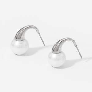 Detailed view of silver stainless steel earrings with white round pearls on white background