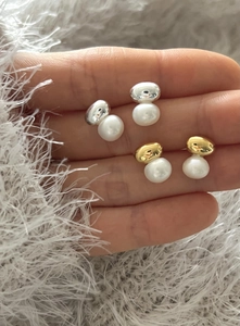 Detailed view of 925 silver pearl stud earrings in gold and silver held in hand
