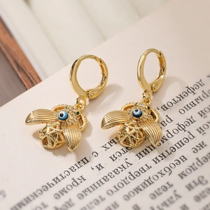 Vintage gold plated bee earrings with blue eye motif displayed on an open book page