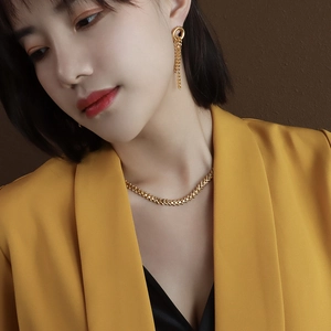 Golden leaf jewelry set with necklace and tassel earrings on model in yellow suit