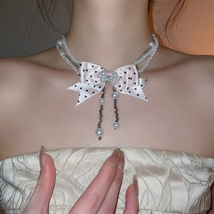 Close-up of a double-layer pearl choker with a pink polka dot bow and rhinestone detail