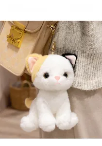 Detailed view of a calico plush cat keychain hanging on a beige shoulder bag as a gift