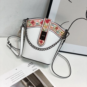 Close-up of floral embroidery on a white PU leather bucket bag with metal chain detail
