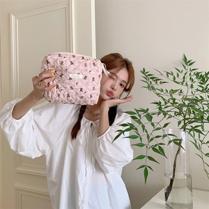 Détail de la trousse de maquillage rose matelassée avec imprimés d'ours et zip