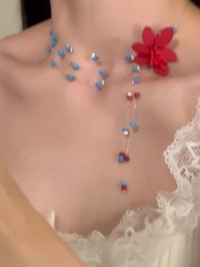 Detail der Perlenkette mit blauen Samenperlen und großem roten 3D-Blumenanhänger