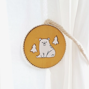 Wooden magnetic curtain tieback featuring a white bear and tree design on a woven rope