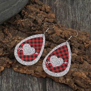 Detail view of teardrop buffalo plaid leather earrings with a glittery arrow heart